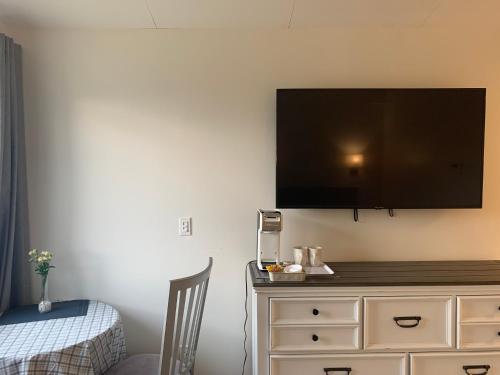 a flat screen tv on a wall above a dresser at Destination Inn Cache Creek in Cache Creek