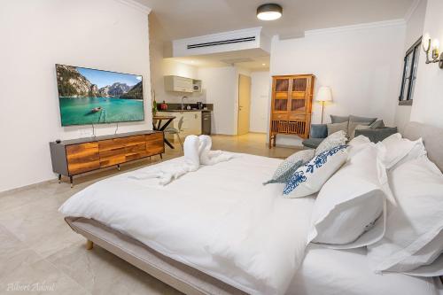 a bedroom with a large white bed with a flat screen tv at סוויטות נוף לתבור in Giv'at Avni