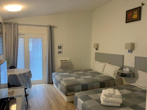 a hotel room with two beds and a television at Destination Inn Cache Creek in Cache Creek