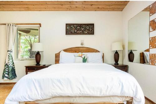 a bedroom with a large white bed and two lamps at A'a- Hale Kumu La'au in Volcano