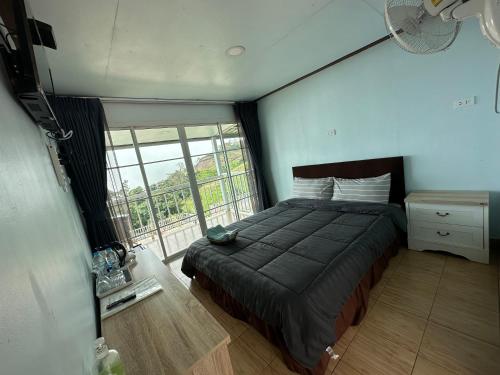a bedroom with a bed and a large window at สเตชั่นภูทับเบิก-บ้านดาดฟ้าทะเลหมอก in Ban Tha Kok Hai
