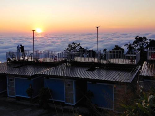 a view of a house with the sun rising above the clouds at สเตชั่นภูทับเบิก-บ้านดาดฟ้าทะเลหมอก in Ban Tha Kok Hai