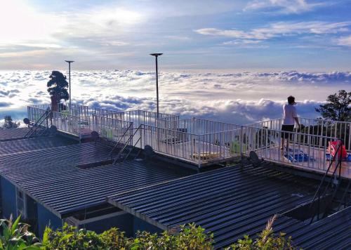 a man standing on top of a viewing platform above the clouds at สเตชั่นภูทับเบิก-บ้านดาดฟ้าทะเลหมอก in Ban Tha Kok Hai