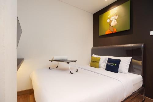 una camera da letto con un letto bianco e un tavolo sopra di Urbanview Hotel Groovy Inn Tangerang a Buaran