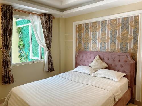 a bedroom with a bed with a pink headboard and a window at Royal Hotel in Ho Chi Minh City
