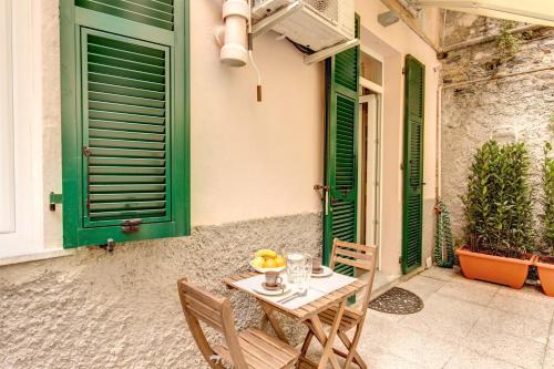 una mesa y sillas en un patio con persianas verdes en Cinque Terre Step, en La Spezia