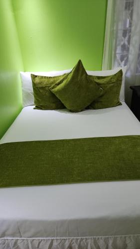 ein Bett mit grünen Wänden und zwei Kissen darauf in der Unterkunft Comfort Zone in Montego Bay