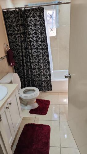 a bathroom with a toilet and a shower curtain at Comfort Zone in Montego Bay