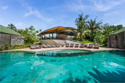 a swimming pool in front of a house with a building at De Moksha Eco Friendly Boutique Resort in Tanah Lot