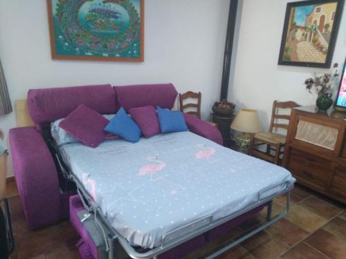 uma cama numa sala de estar com um sofá roxo em Almajar 4 em El Puerto de Santa María