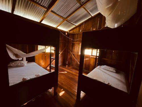 two bunk beds in a room with wooden floors at Onda Hostel Mompiche in Mompiche