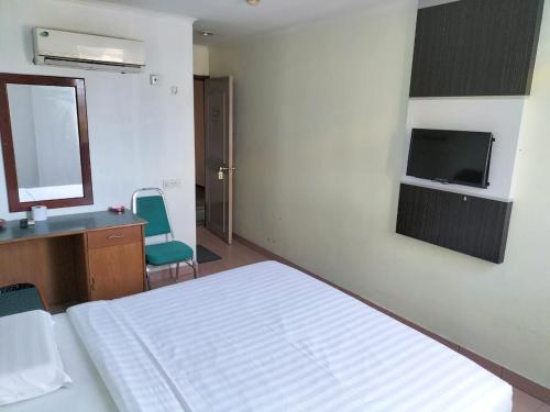 1 dormitorio con cama, escritorio y espejo en Faber Inn, en Bintulu