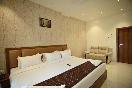 um quarto com uma cama grande e uma cadeira em The Sky Land Hotel & Restaurant em Tuljapur