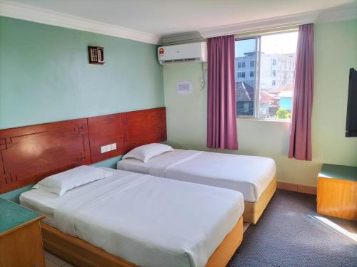 um quarto com duas camas e uma janela em Faber Inn em Bintulu