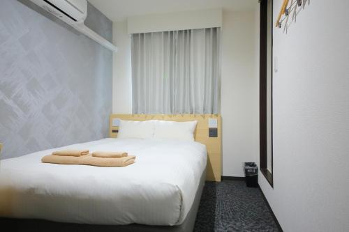 ein Hotelzimmer mit einem Bett, auf dem Handtücher liegen in der Unterkunft Hotel Shin-Imamiya in Osaka