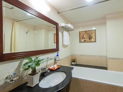 uma casa de banho com um lavatório, um espelho e uma banheira em Lefoyer Hotel em Hanói