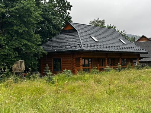 a log cabin with a black roof in a field at Chalet PidStromom in Mykulychyn