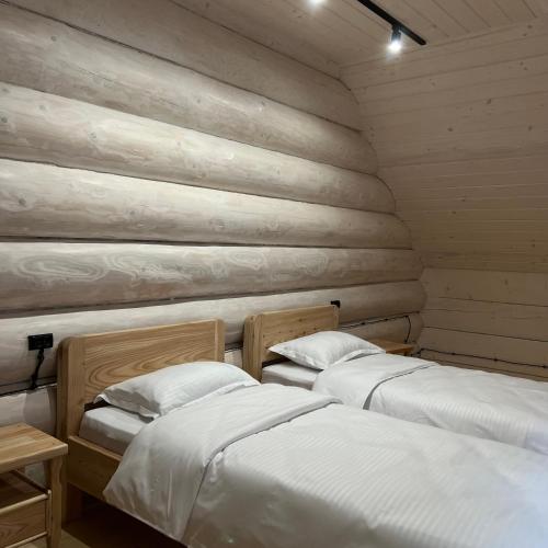 two beds in a room with wooden walls at Chalet PidStromom in Mykulychyn