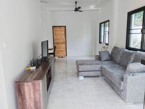 sala de estar con sofá y TV de pantalla plana en Okat pool villa khanom, en Khanom