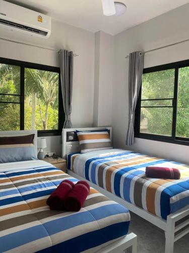 two beds in a room with two windows at Okat pool villa khanom in Khanom