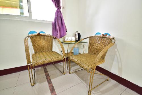 two rattan chairs and a glass table in a room at Xi Cun Homestay in Donghe