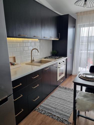a kitchen with black cabinets and a sink at La Cetate Luxury Apartment in Ipoteşti