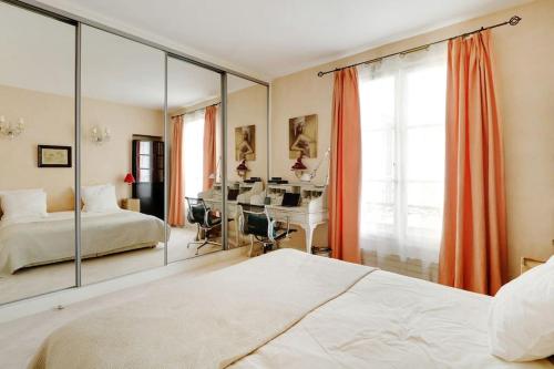 - une chambre avec un miroir, un lit et un bureau dans l'établissement Séjour au pied de la tour Eiffel, à Paris