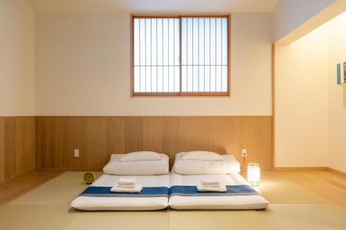 two beds in a room with a window at Irodori Hotel KITSUNE in Fukuoka