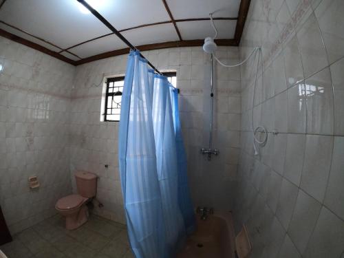 a bathroom with a shower with a blue shower curtain at Nairobi Backpackers Hostel in Nairobi