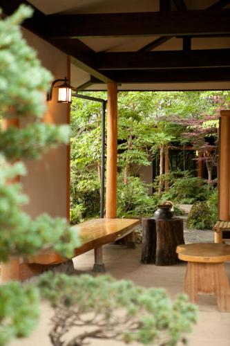 a wooden bench in a garden with trees at Ryoso Yufuin Yamadaya in Yufuin