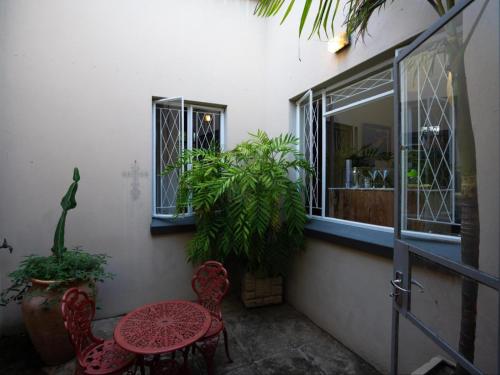 a patio with two chairs and a table and a window at The Art House Victoria Falls in Victoria Falls