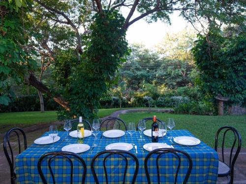 a table with plates and wine bottles on it at The Art House Victoria Falls in Victoria Falls
