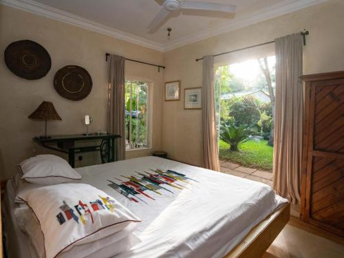 Un dormitorio con una cama con almohadas de colores y una ventana en The Art House Victoria Falls en Victoria Falls