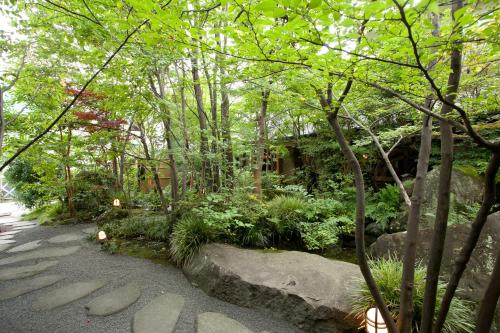 a garden with rocks and trees and a building at Ryoso Yufuin Yamadaya in Yufuin