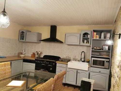 cocina con electrodomésticos blancos y mesa de cristal en Maison traditionnelle en Lozère, en Saint-Saturnin-de-Tartaronne