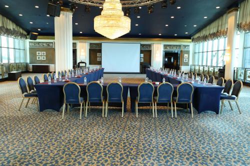 a conference room with blue tables and chairs and a screen at Le Royal Hotel - Beirut in Beirut