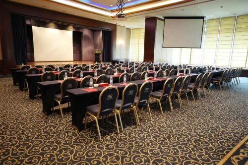 a conference room with tables and chairs and a screen at Le Royal Hotel - Beirut in Beirut