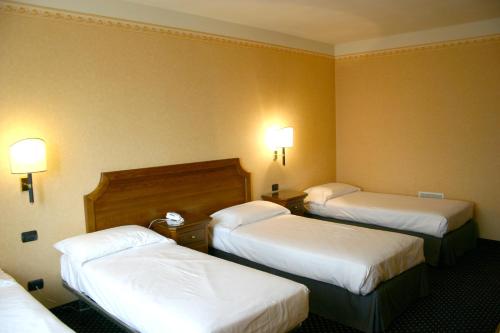 a hotel room with three beds and lights on the wall at Hotel Don Carlo in Broni