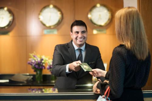 a man in a suit is handing money to a woman at Le Royal Hotel - Beirut in Beirut