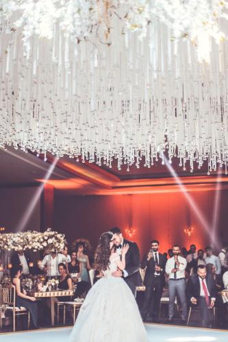 a bride and groom kissing under a chandelier at Le Royal Hotel - Beirut in Beirut