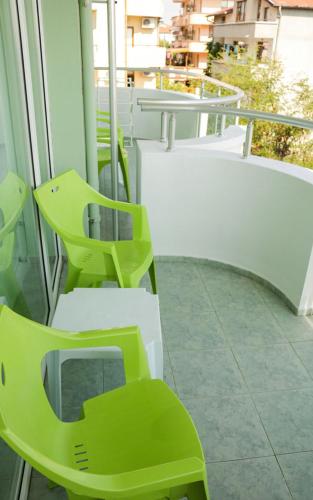a couple of green chairs sitting on a balcony at Хотел Марта in Primorsko