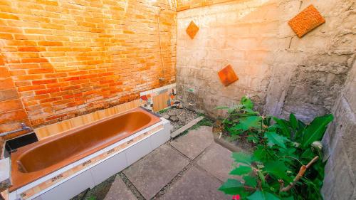 y baño con bañera junto a una pared de ladrillo. en Rumah Gaharu - Kamar Kulon, en Bedoyo