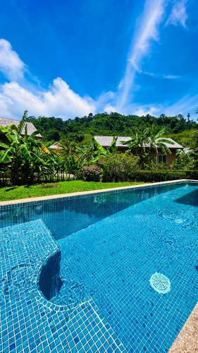 a large blue swimming pool with a house in the background at Peaceful Retreat Villa by Nai Thon beach in Phuket