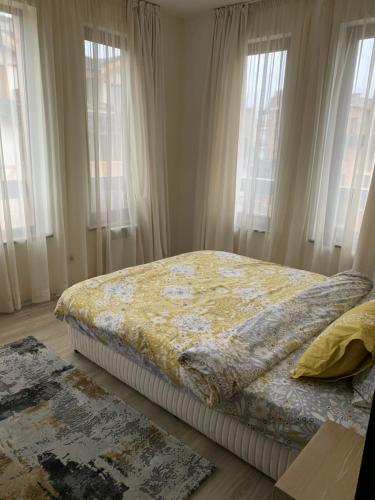 a bed sitting in a bedroom with windows at Private Apartment Pirin Golf Club with Lake View in Razlog