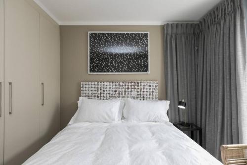 um quarto com uma cama branca e uma fotografia na parede em Business traveler LuxRoom 20Mb WiFi 2km 2 gautrain em Joanesburgo
