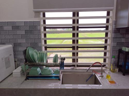 uma cozinha com um lavatório e um banco com uma janela em Villa De Lova - Wakaf Che Yeh em Kota Bharu