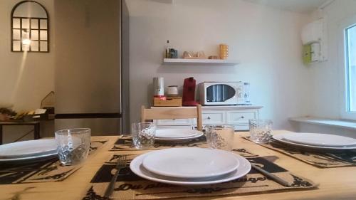 una mesa con platos y vasos encima en La remise des Copains 2 chambres avec Clim OcKeys, en Limoux