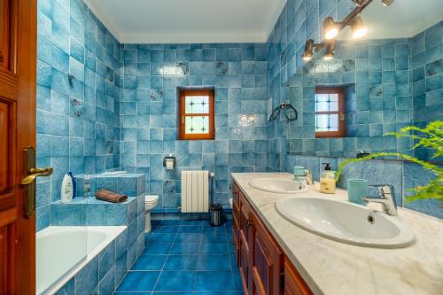 Villa Can Joan den Coves في سانتا غيرتوديس دي فروريتا: حمام من البلاط الأزرق مع حوض استحمام ومغسلة