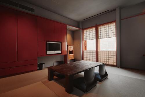 a room with a table and a tv and red cabinets at River Retreat Garaku in Toyama