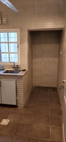 eine leere Küche mit einem Waschbecken und einem Fenster in der Unterkunft مسقط الوادي الكبير in Wādī Kabīr
